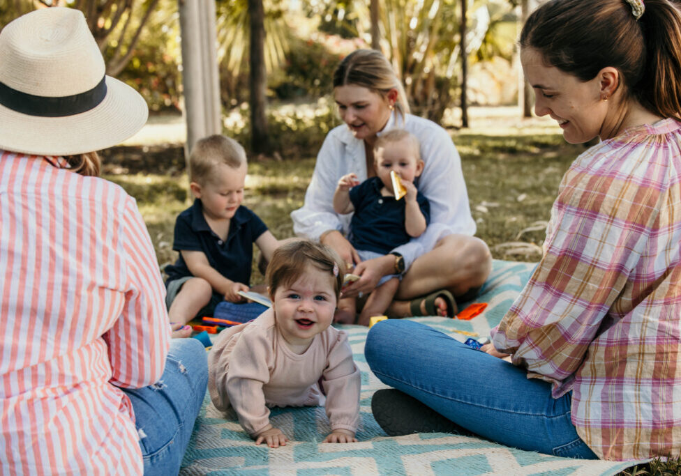 Parents sitting together with young babies, engaging in activities that support baby brain development through play and connection.