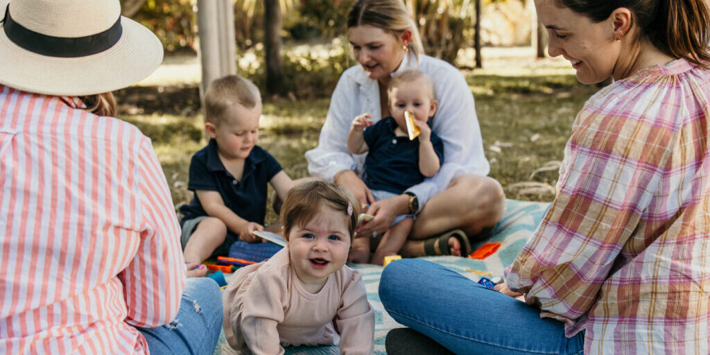 Parents sitting together with young babies, engaging in activities that support baby brain development through play and connection.