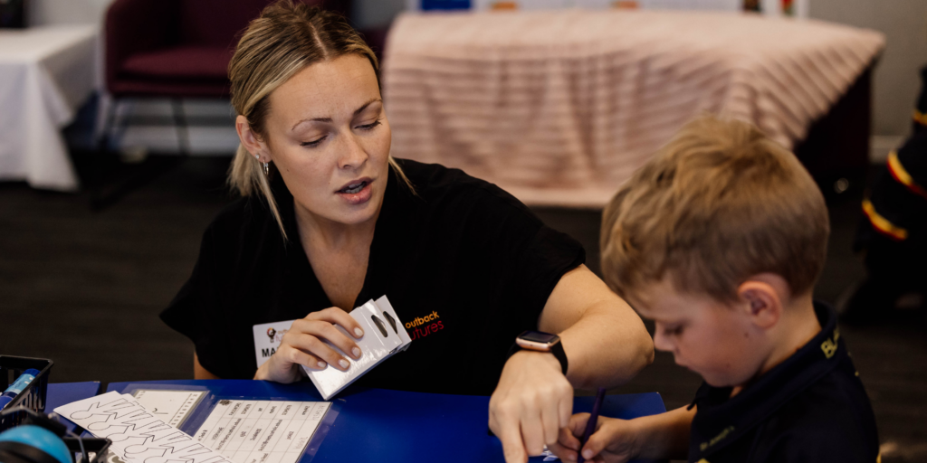 Speech pathologist conducting an early years developmental screening with a young child in a learning environment.